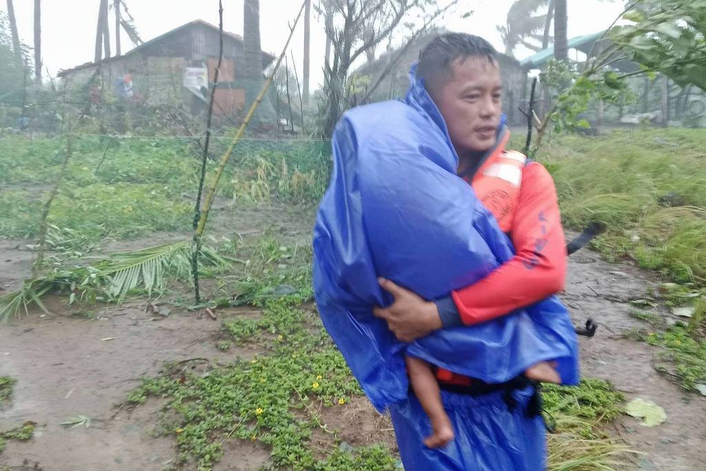 In this photo provided by the Philippine Coast Guard, a rescuer evacuates a child to safer grounds as Super Typhoon Ragasa affects Santa Ana, Cagayan province, northern Philippines, Monday, Sept. 22, 2025. (Philippine Coast Guard via AP)