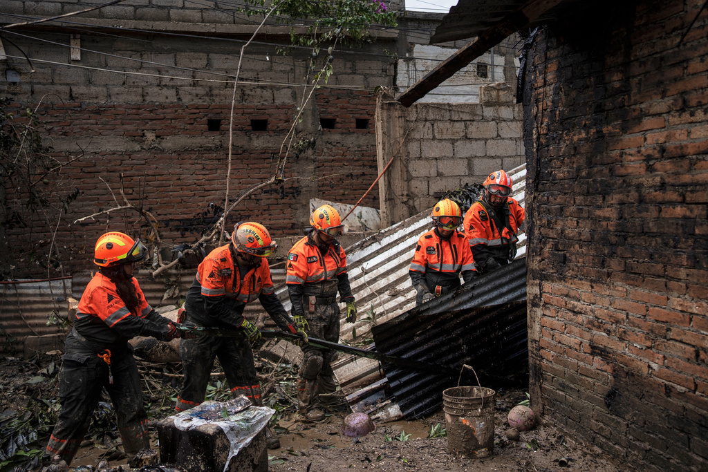 Rescue workers, part of the volunteer brigade known as the Topos, clean a damaged house in Poza Rica, Mexico, Monday, Oct. 13, 2025, after torrential rains. (AP Photo/Felix Marquez)