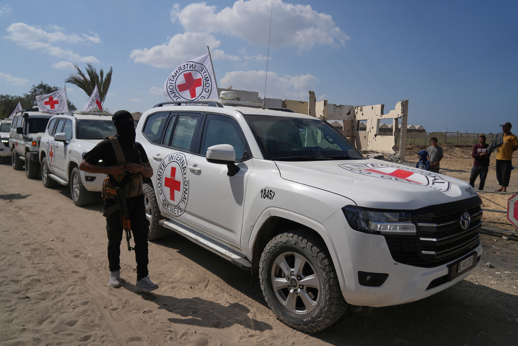 A masked Hamas gunman stands next to Red Cross vehicles arriving for the handover of Israeli hostages by Hamas, in Khan Younis, southern Gaza Strip, Monday, Oct. 13, 2025. (AP Photo/Abdel Kareem Hana)