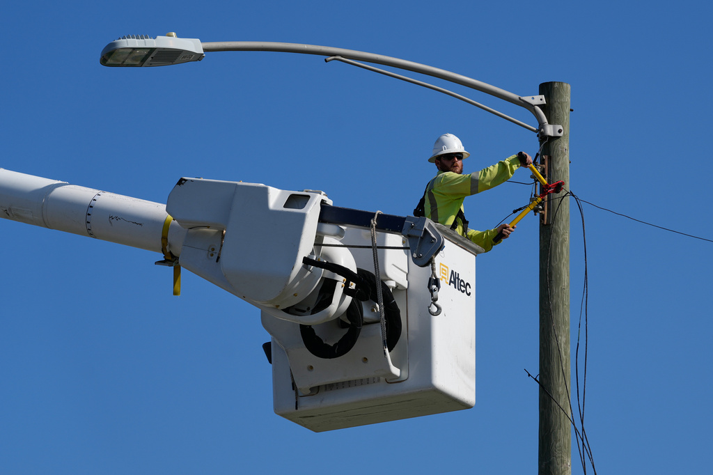 An electrical worker repairs power lines along a street in Gary, Ind, Thursday, Aug. 20, 2026, more than a week after a deadly storm passes through the area. (AP Photo/Nam Y. Huh)