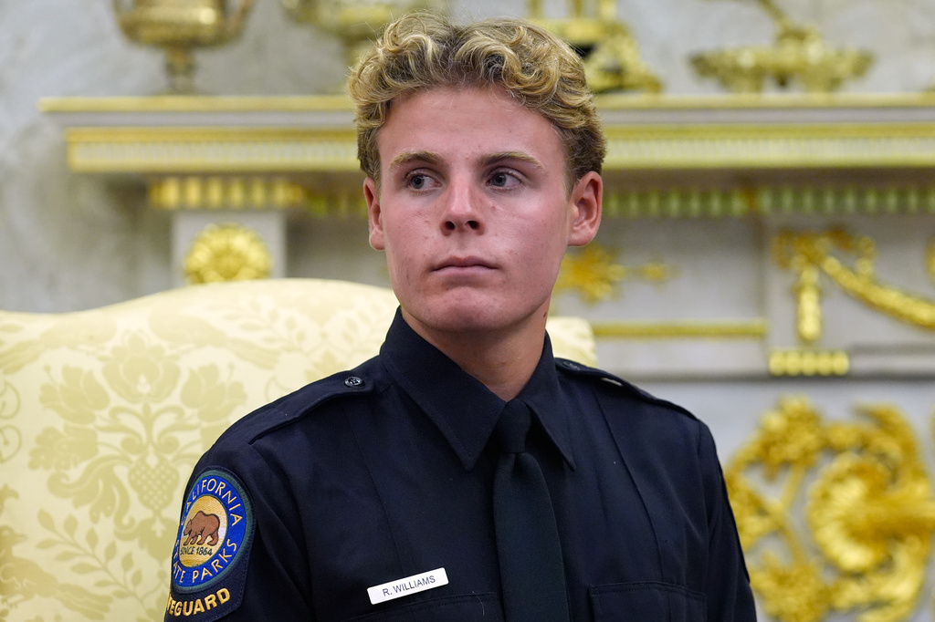 Lifeguard Ryder Williams listens as he meets with President Donald Trump in the Oval Office of the White House, Monday, Aug. 17, 2026, in Washington. (AP Photo/Manuel Balce Ceneta)