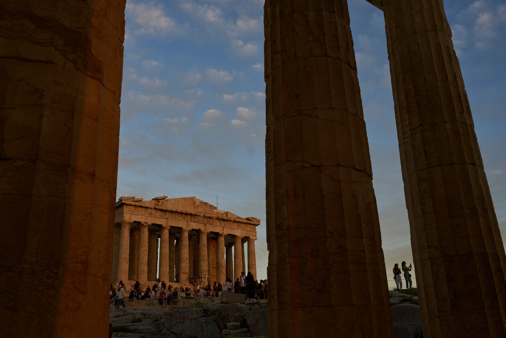 Tourists visit the Acropolis hill as the 5th century B.C. Parthenon temple, free of scaffolding, stands in the background in Athens, Sunday, Oct. 26, 2025. (AP Photo/Petros Giannakouris)