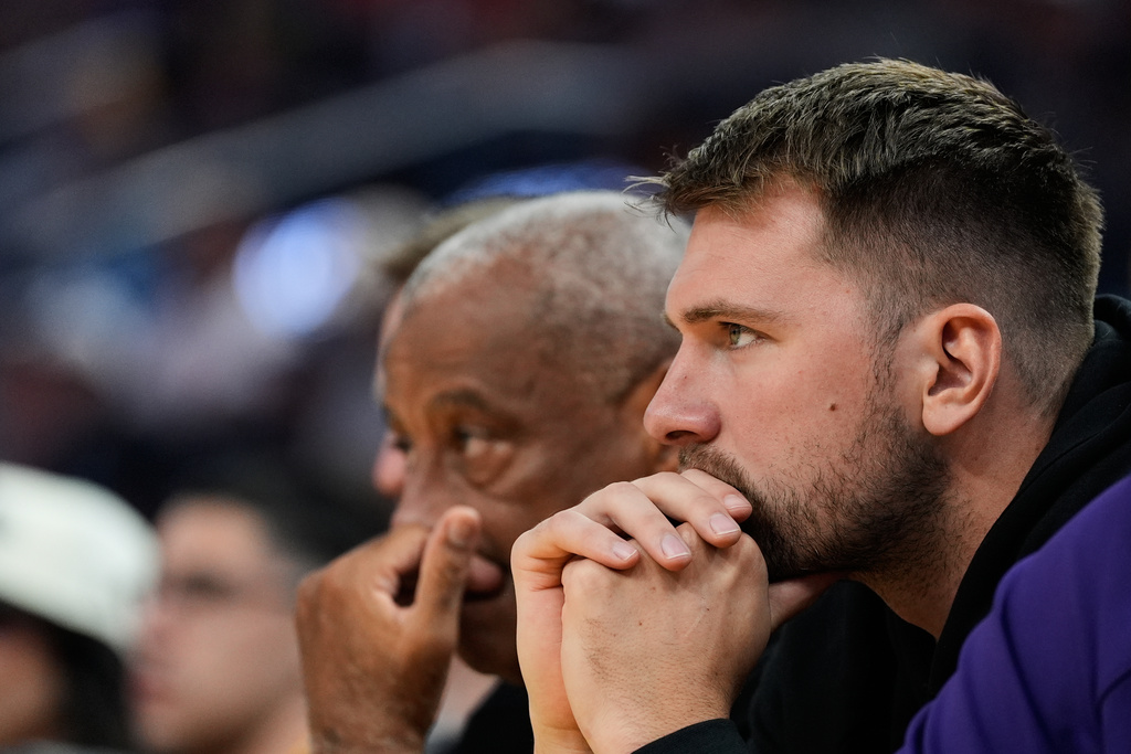 Los Angeles Lakers' Luka Dončić watches from the bench during the first half of an NBA basketball preseason game against the Golden State Warriors, Sunday, Oct. 5, 2025, in San Francisco. (AP Photo/Godofredo A. Vásquez)