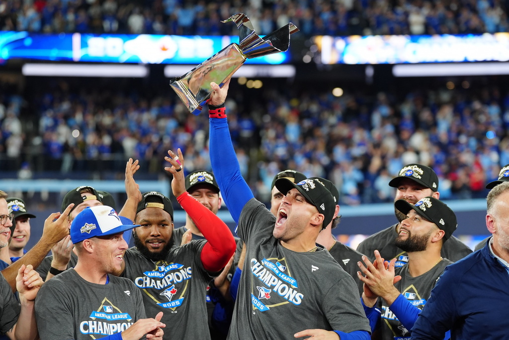 Toronto Blue Jays' George Springer holds the American League Championship Series trophy as the team celebrates after defeating the Seattle Mariners in Game 7 of the series in Toronto, Monday, Oct. 20, 2025. (Frank Gunn/The Canadian Press via AP)