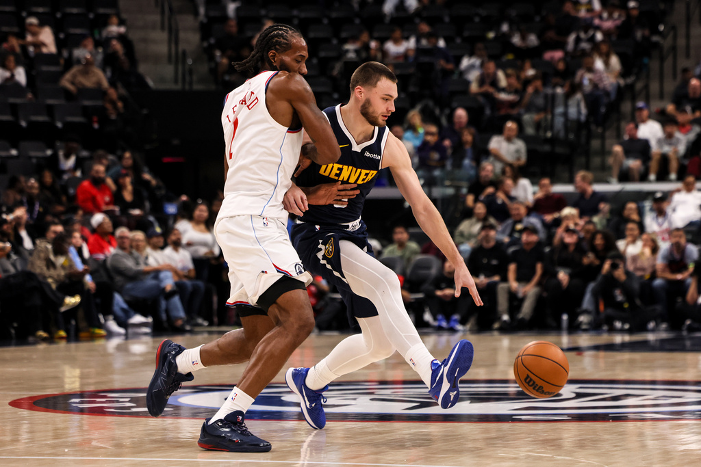 Denver Nuggets guard Christian Braun, right, dribbles past Los Angeles Clippers forward Kawhi Leonard during the first half of a preseason NBA basketball game, Sunday, Oct. 12, 2025, in Inglewood, Calif. (AP Photo/Etienne Laurent)
