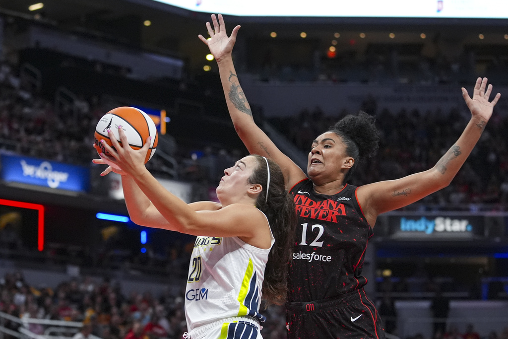 Dallas Wings forward Maddy Siegrist (20) shoots in front of Indiana Fever forward Damiris Dantas (12) in the first half of a WNBA basketball game in Indianapolis, Tuesday, Aug. 12, 2025. (AP Photo/Michael Conroy)