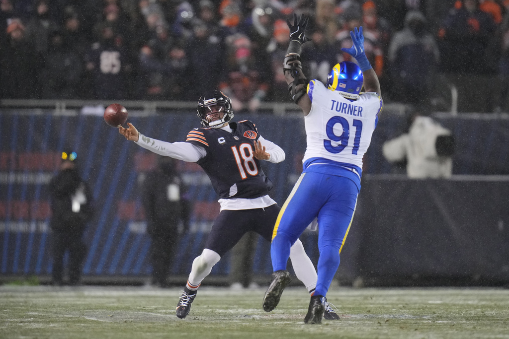 Chicago Bears quarterback Caleb Williams (18) throws a pass as Los Angeles Rams defensive end Kobie Turner (91) applies pressure during the second half of an NFL football divisional playoff game Sunday, Jan. 18, 2026, in Chicago. (AP Photo/Jeff Roberson)
