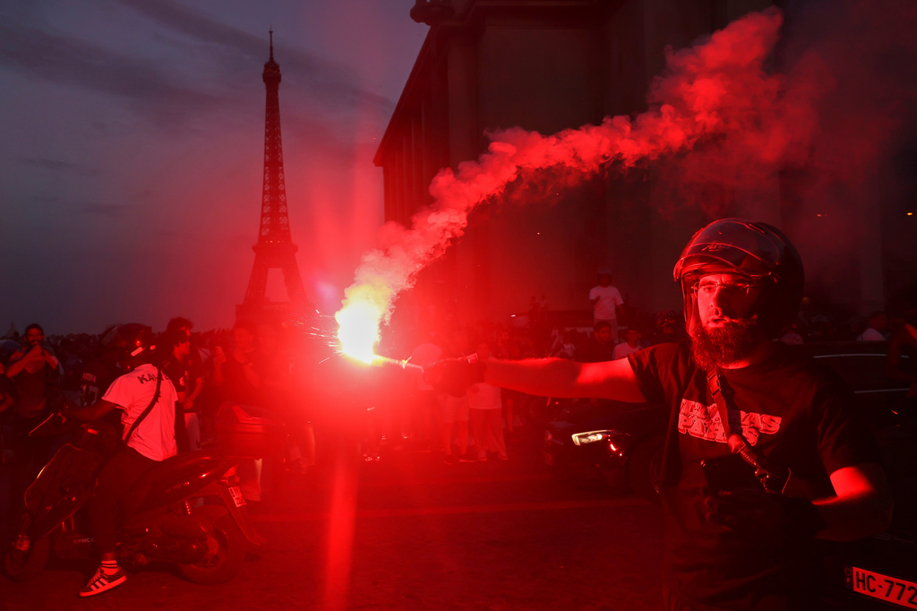 A man holds a flare as PSG supporters celebrate in Paris, Saturday, May 30, 2026 after the Champions League final soccer match between Paris Saint-Germain and Arsenal that's being played in Budapest., PSG won the game. (AP Photo/Thomas Padilla)