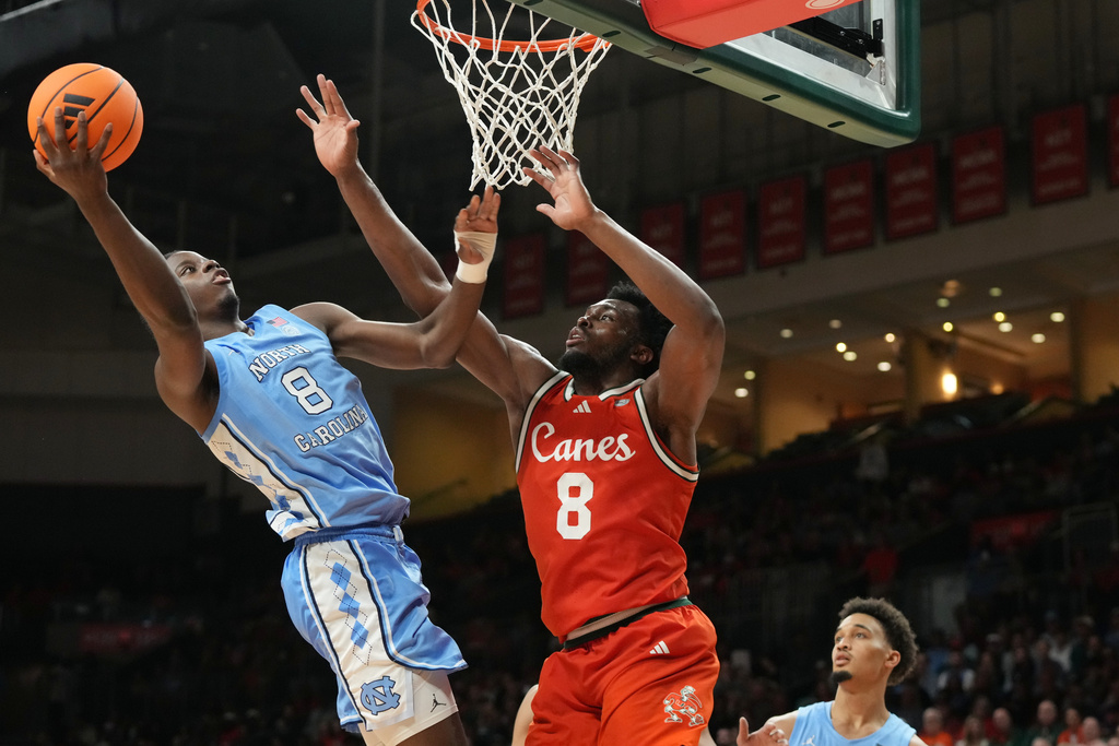 North Carolina forward Caleb Wilson (8) drives to the basket as Miami center Ernest Udeh Jr. (8) defends during the first half of an NCAA college basketball game, Tuesday, Feb. 10, 2026, in Coral Gables, Fla. (AP Photo/Marta Lavandier)