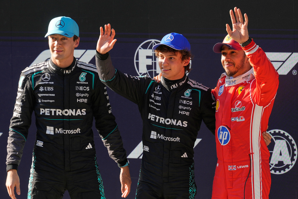 Mercedes driver Andrea Kimi Antonelli of Italy, center, waves after getting the pole position beside Mercedes driver George Russell, left, of Britain and Ferrari driver Lewis Hamilton of Britain during the qualifying session of the Chinese Formula One Grand Prix at the Shanghai International Circuit, in Shanghai, China, Saturday, March 14, 2026. (AP Photo/Vincent Thian)