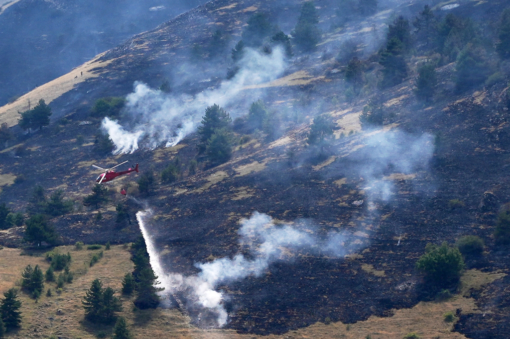 A firefighting helicopter drops water on a wildfire on a mountain near L'Aquila, central Italy, Monday, Aug. 3, 2026. (AP Photo/Andrea Rosa)