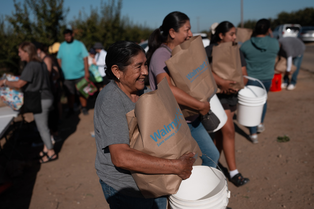 Guadalupe Martinez smiles after getting a bag of nectarines during a free giveaway at Cesar Mora's orchard in Reedley, Calif., Wednesday, July 1, 2026. (AP Photo/Jae C. Hong)