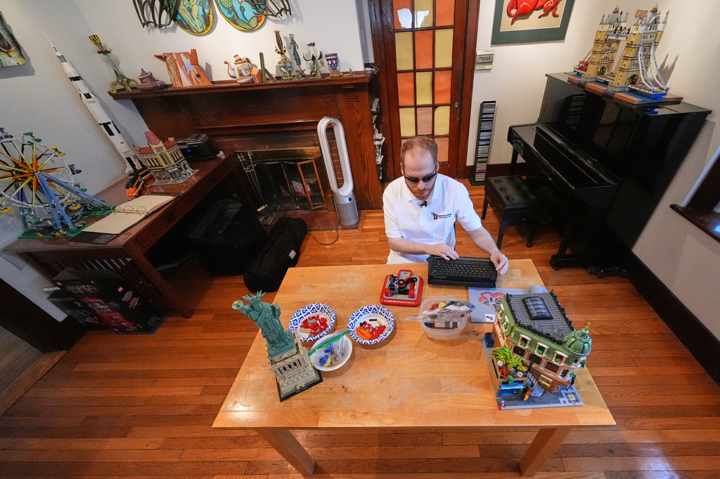Matthew Shifrin, the founder of Bricks for the Blind, reads from a braille terminal while building a LEGO project at his family's home, Friday, March 20, 2026, in Newton, Mass. (AP Photo/Charles Krupa)