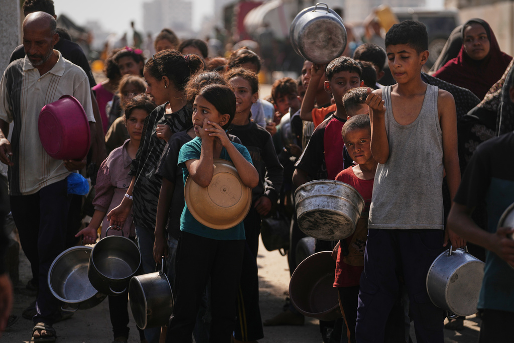 Palestinians wait to receive donated food at a community kitchen in Gaza City, Thursday, Oct. 23, 2025. (AP Photo/Abdel Kareem Hana)