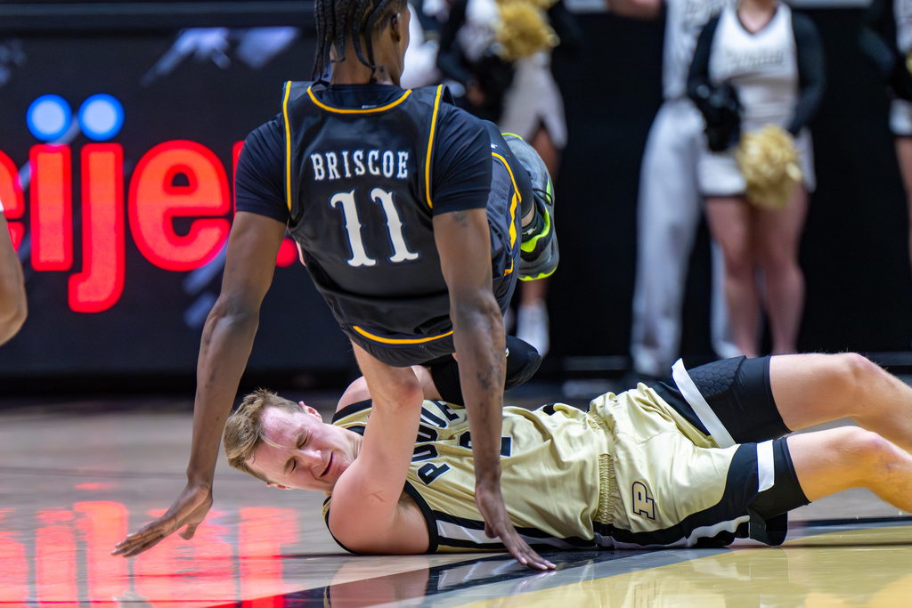 Kent State center Dezmon Briscoe (11) stumbles over Purdue guard Fletcher Loyer, bottom, at midcourt during the first half of an NCAA college basketball game, Monday, Dec. 29, 2025, in West Lafayette, Ind. (AP Photo/Doug McSchooler)