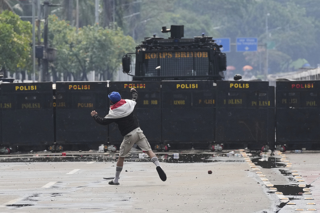 A protester throws rock at the police during a protest against lavish allowances given to parliament members, outside the parliament in Jakarta, Indonesia, Sunday, Aug. 31, 2025. (AP Photo/Dita Alangkara)