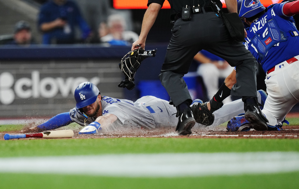 Los Angeles Dodgers' Alex Freeland, left, slides in safely at home ahead of the tag from Toronto Blue Jays catcher Brandon Valenzuela (59) during the ninth inning of an MLB baseball game in Toronto on Tuesday, April 7, 2026. (Nathan Denette/The Canadian Press via AP)