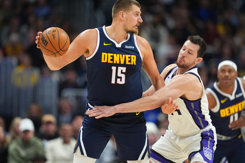 Denver Nuggets center Nikola Jokic, left, looks to pass the ball as Sacramento Kings forward Drew Eubanks defends in the first half of an NBA basketball game Monday, Nov. 3, 2025, in Denver. (AP Photo/David Zalubowski)