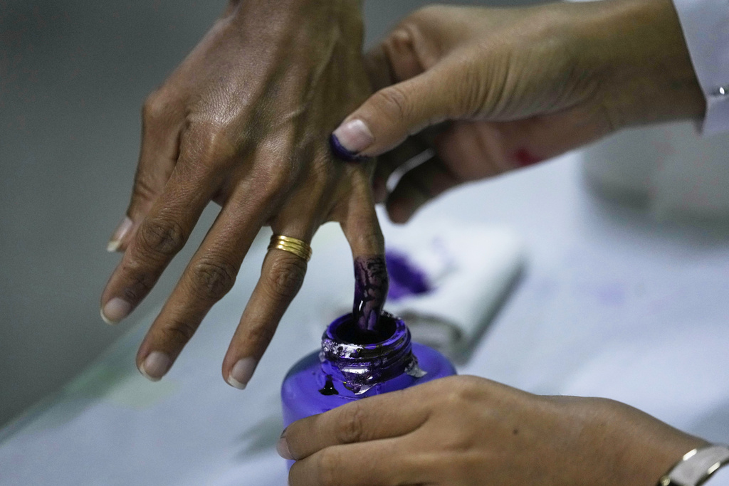 A voter dips their finger in an ink bottle after casting a ballot at a polling station in Naypyitaw, Myanmar, Sunday, Dec. 28, 2025. (AP Photo/Aung Shine Oo)