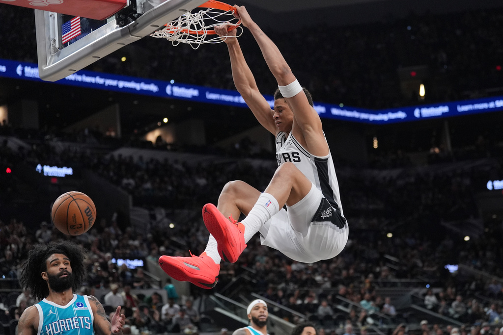San Antonio Spurs forward Carter Bryant (11) scores over Charlotte Hornets guard Coby White (3) during the first half of an NBA basketball game in San Antonio, Saturday, March 14, 2026. (AP Photo/Eric Gay)