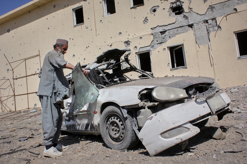A man inspects a car damaged after a Pakistani strike in on a refugee camp in Takhta Pul district, Kandahar province, Afghanistan, Saturday, Feb. 28, 2026. (AP Photo/Sibghatullah)