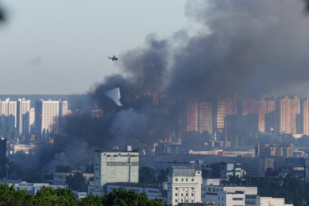 A helicopter drops water from a drop tank onto a fire at a market after a Russian strike on Kyiv, Ukraine, on Monday, June 15, 2026. (AP Photo/Evgeniy Maloletka)