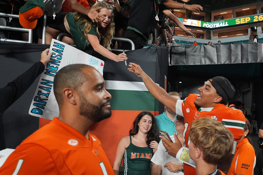 Miami quarterback Darian Mensah, right, signs autographs after an NCAA college football game against Florida A&M, Thursday, Sept. 10, 2026, in Miami Gardens, Fla. (AP Photo/Lynne Sladky)