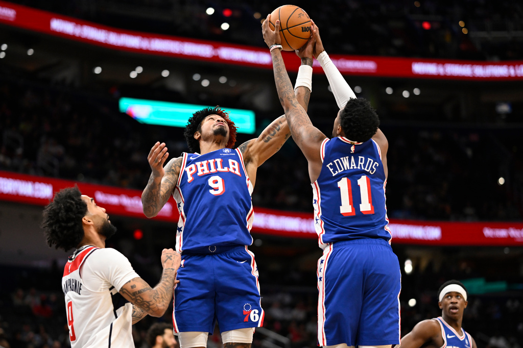 Philadelphia 76ers guard Kelly Oubre Jr. (9) and 76ers forward Justin Edwards (11) compete for a rebound over Washington Wizards forward Justin Champagnie during the first half of an NBA basketball game, Wednesday, April 1, 2026, in Washington. (AP Photo/John McDonnell)