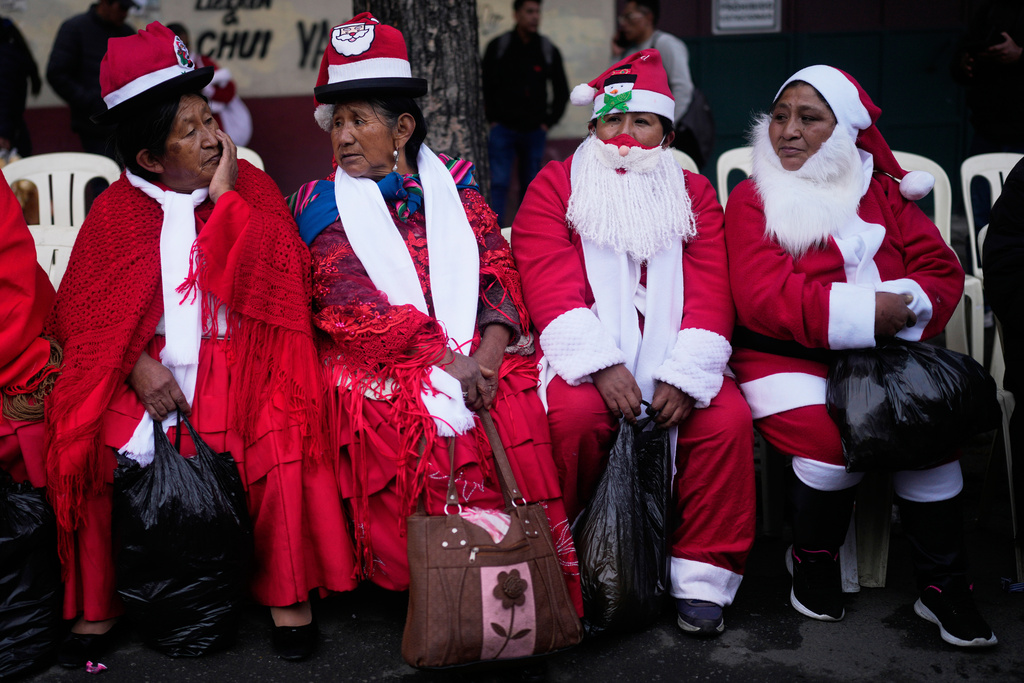 FILE - Women dressed as Santa Claus rest before the Christmas parade in La Paz, Bolivia, Dec. 3, 2025. (AP Photo/Juan Karita, File)