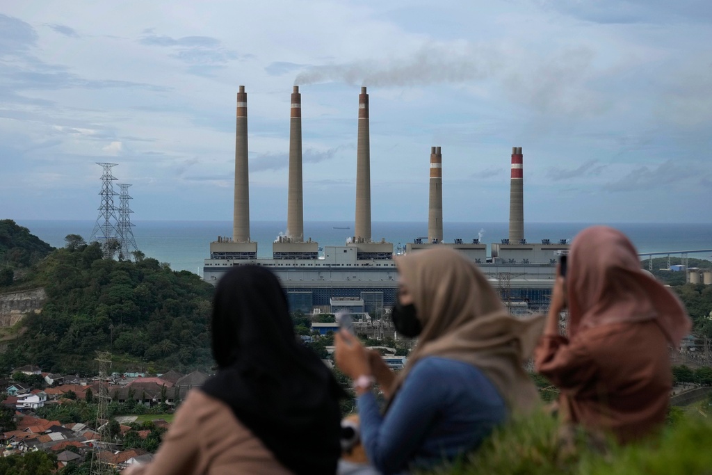 FILE - Women sit on a hill overlooking the Suralaya coal power plant in Cilegon, Indonesia, Jan. 8, 2023. (AP Photo/Dita Alangkara, File)