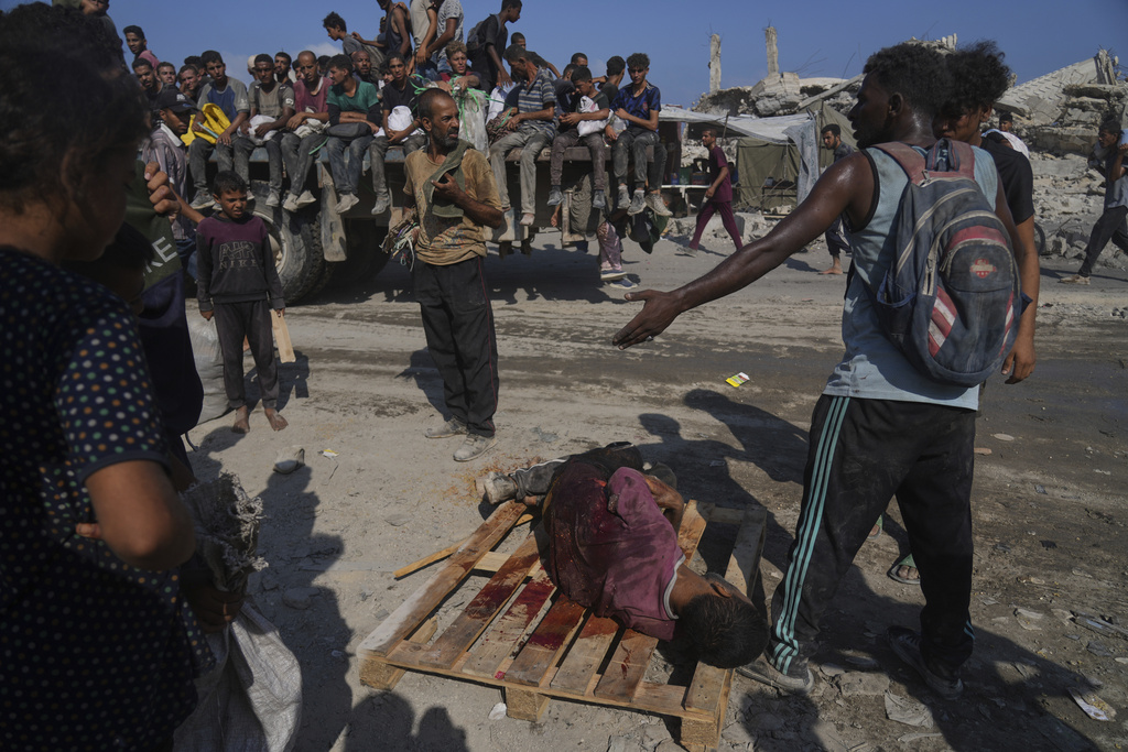 Palestinians carry a man injured while trying to reach a humanitarian aid convoy on the outskirts of Beit Lahiya in the northern Gaza Strip, Saturday, Aug. 23, 2025. (AP Photo/Abdel Kareem Hana)