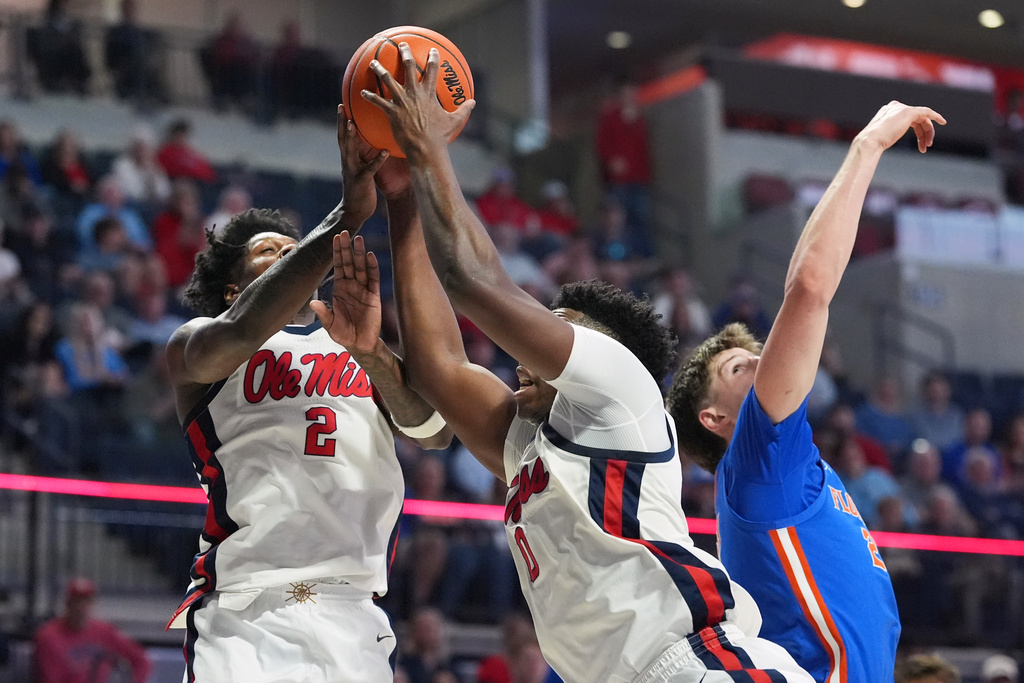 Mississippi guard AJ Storr (2) and forward Malik Dia (0) reach past Florida's Alex Condon to haul down a rebound during the first half of an NCAA college basketball game, Saturday, Feb. 21, 2026, in Oxford, Miss. (AP Photo/Rogelio V. Solis)