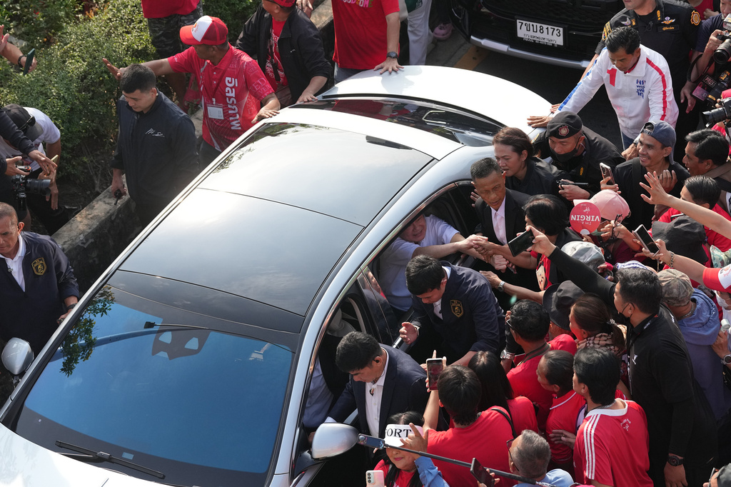 Former Thailand Prime Minister Thaksin Shinawatra shakes hands with his supporters from inside a car after he was released from a Bangkok prison in Bangkok, Thailand, Monday, May 11, 2026. (AP Photo/Sakchai Lalit)