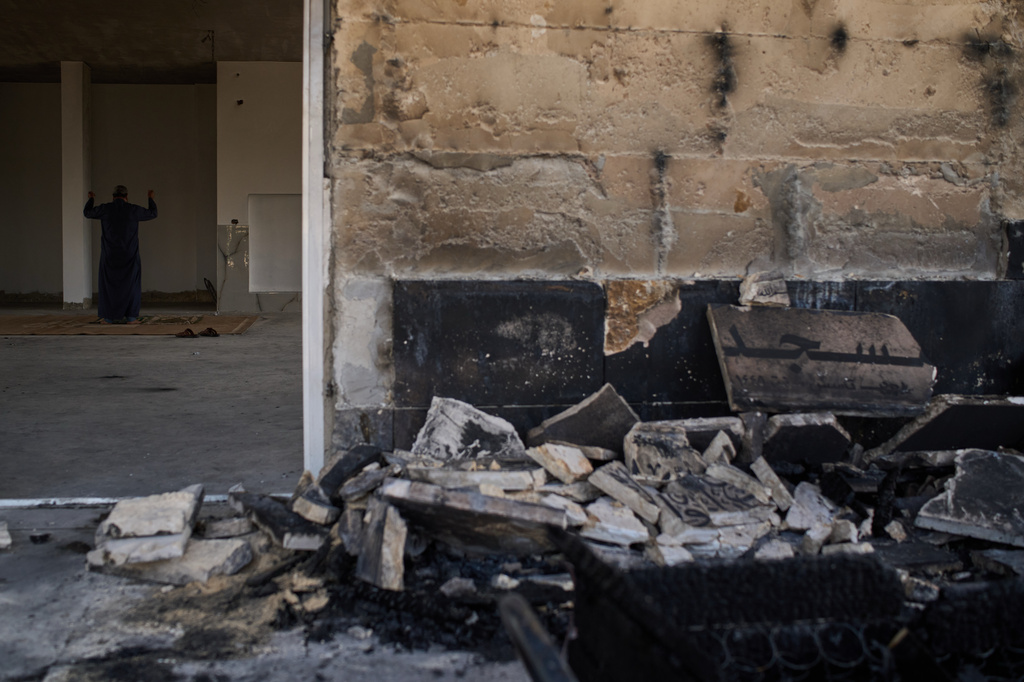 A Palestinian man prays inside a mosque that was burned during an attack by Israeli settlers early in the morning in the West Bank village of Qusra, Sunday, July 26, 2026. (AP Photo/Leo Correa)