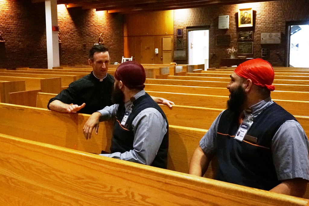 The Rev. Brian Daley speaks with two airline employees after they prayed at Our Lady of the Airways, a Catholic chapel at Logan International Airport, in Boston, Friday, Aug. 29, 2025. (AP Photo/Giovanna Dell'Orto)
