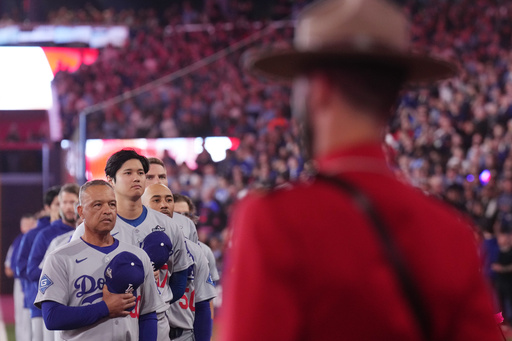 Los Angeles Dodgers manager Dave Roberts, left, two-way player Shohei Ohtani (17) and shortstop Mookie Betts (50) listen to the Canadian national anthem as Royal Canadian Mounted Police look on, ahead of the first inning Royal Canadian Mounted Police in Game 1 of baseball's World Series, Friday, Oct. 24, 2025, in Toronto. (Nathan Denette/The Canadian Press via AP) Los Angeles Dodgers manager Dave Roberts, left, two-way player Shohei Ohtani (17) and shortstop Mookie Betts (50) listen to the Canadian national anthem as Royal Canadian Mounted Police look on, ahead of the first inning Royal Canadian Mounted Police in Game 1 of baseball's World Series, Friday, Oct. 24, 2025, in Toronto. (Nathan Denette/The Canadian Press via AP)