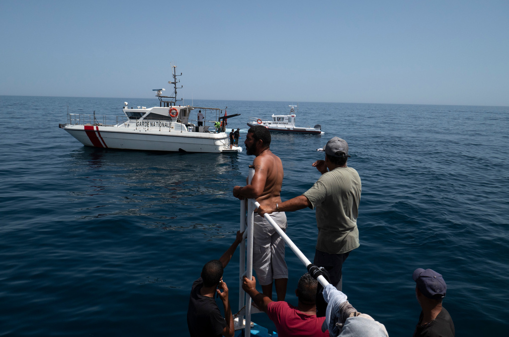 Boats of fishermen and Tunisian national guard approach a drowned body during a search operation after a boat carrying migrants capsized off the country's southeastern coast, near Zarzis, Tunisia, Sunday, Aug. 23, 2026. (AP Photo/Bassem Aouini)