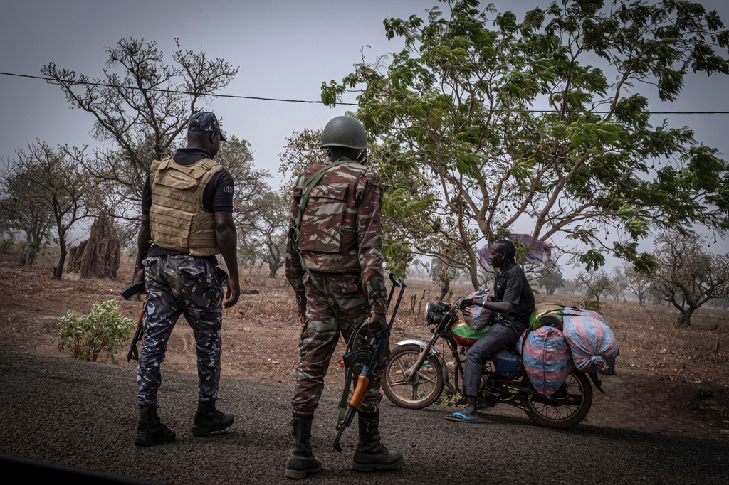 FILE - A police officer and a soldier from Benin stop a motorcyclist at a checkpoint, outside Porga, Benin, March 26, 2022. (AP Photo/ Marco Simoncelli, File)