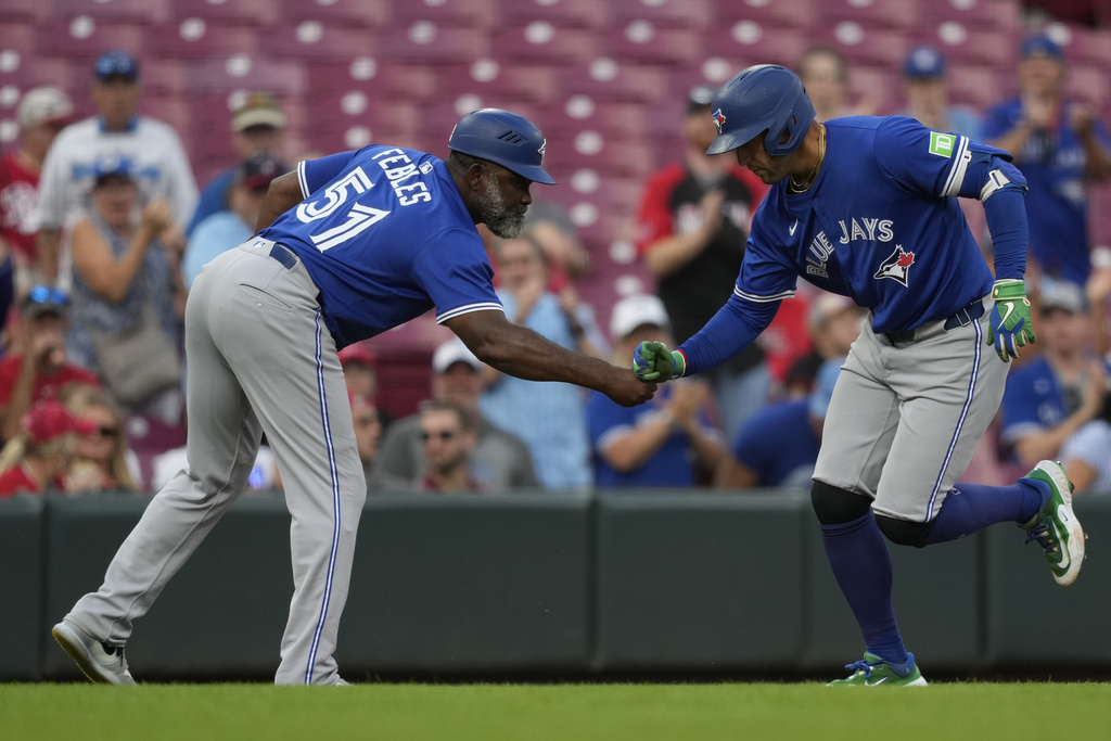 Toronto Blue Jays' George Springer, right, celebrates with third base coach Carlos Febles as he rounds the bases after hitting a solo home run during the third inning of a baseball game against the Cincinnati Reds Wednesday, Sept. 3, 2025, in Cincinnati. (AP Photo/Carolyn Kaster)