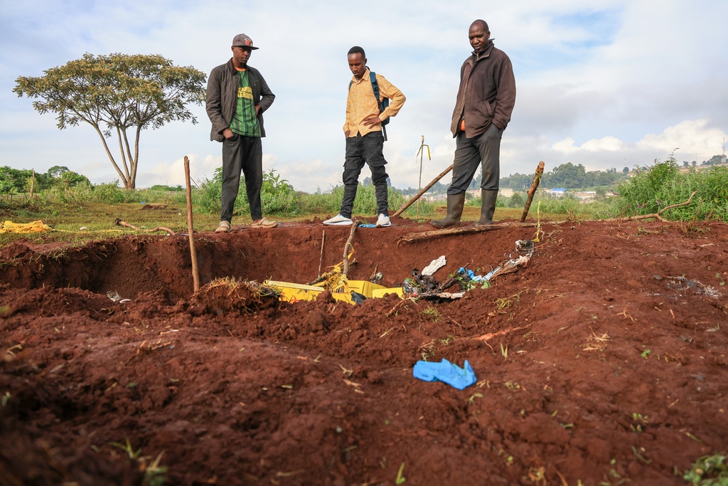 People gather at the scene of a mass grave where 33 bodies were exhumed at a cemetery in Kericho, Western Kenya Thursday, March 26, 2026. (AP Photo/Andrew Kasuku)
