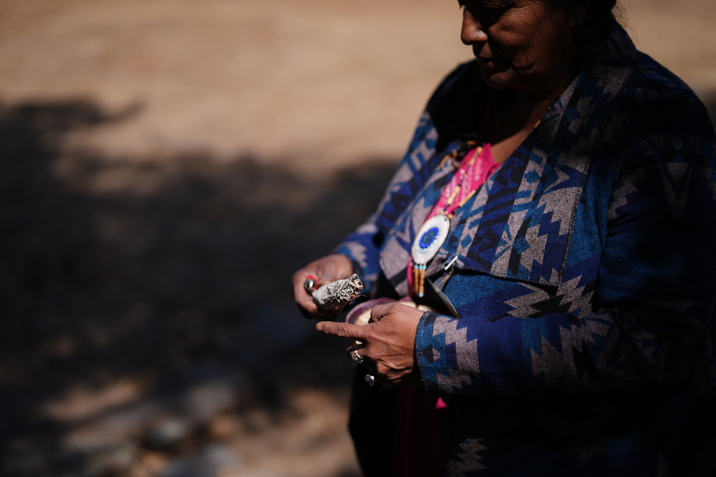 Norma Meza Calles, a Kumeyaay Nation leader, lights a bundle of white sage as she talks of the sacred importance of nearby Kuuchamaa Mountain at a wellness center Friday, May 1, 2026, in Tecate, Mexico. (AP Photo/Gregory Bull)