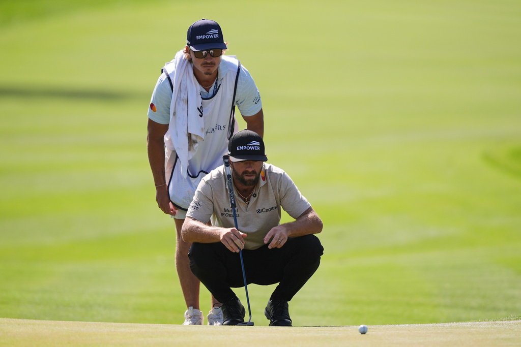 Cameron Young and his caddie line up a shot on the ninth green during the second round of The Players Championship golf tournament Friday, March 13, 2026, in Ponte Vedra Beach, Fla. (AP Photo/Gerald Herbert)