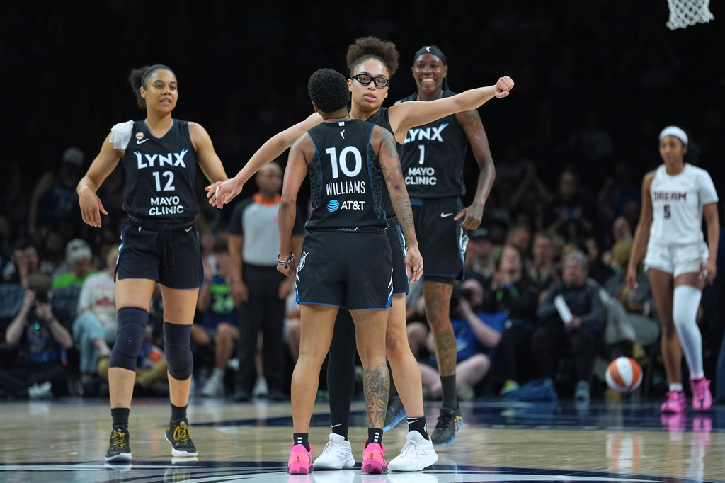 Minnesota Lynx guard Olivia Miles (5), middle, celebrates with guard Courtney Williams (10) after a basket made by forward Natasha Howard (1) during the second half of a WNBA basketball game against the Atlanta Dream Wednesday, May 27, 2026, in Minneapolis. (AP Photo/Abbie Parr)