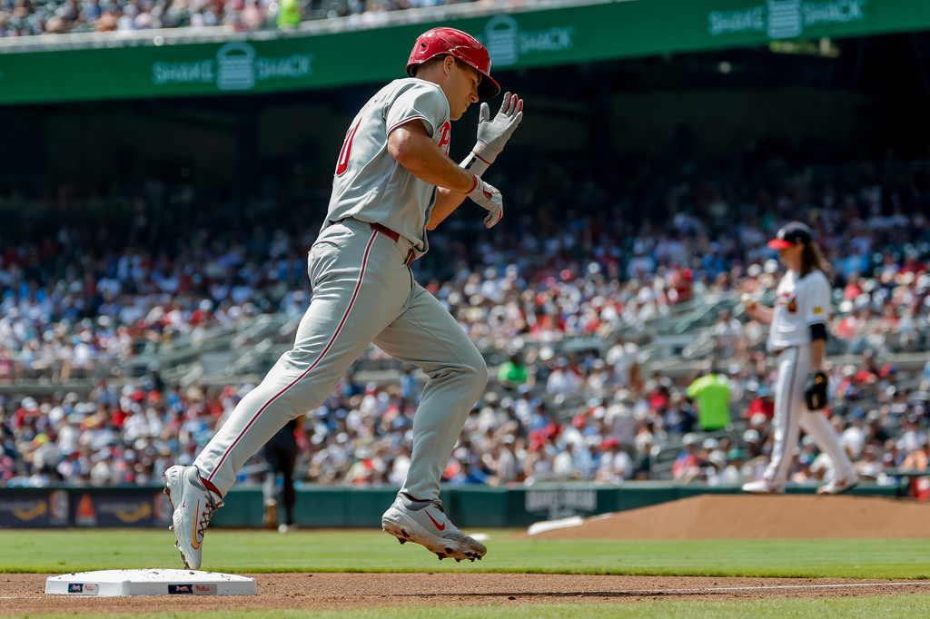 Philadelphia Phillies' J.T. Realmuto, left, reacts while rounding the bases after hitting a two-run home run off Atlanta Braves pitcher Grant Holmes, back right, during the second inning of a baseball game, Sunday, Sept. 13, 2026, in Atlanta. (AP Photo/Erik S. Lesser)