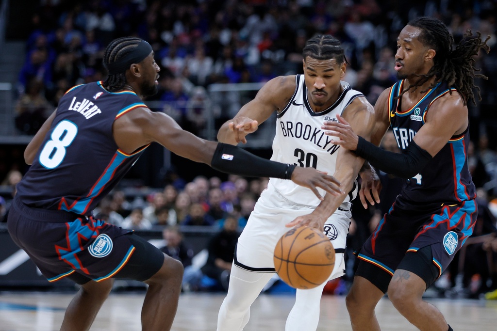 Brooklyn Nets guard Ochai Agbaji (30) tries to drive to the basket between Detroit Pistons guards Caris LeVert (8) and Daniss Jenkins, right, during the first half of an NBA basketball game Saturday, March 7, 2026, in Detroit. (AP Photo/Duane Burleson)