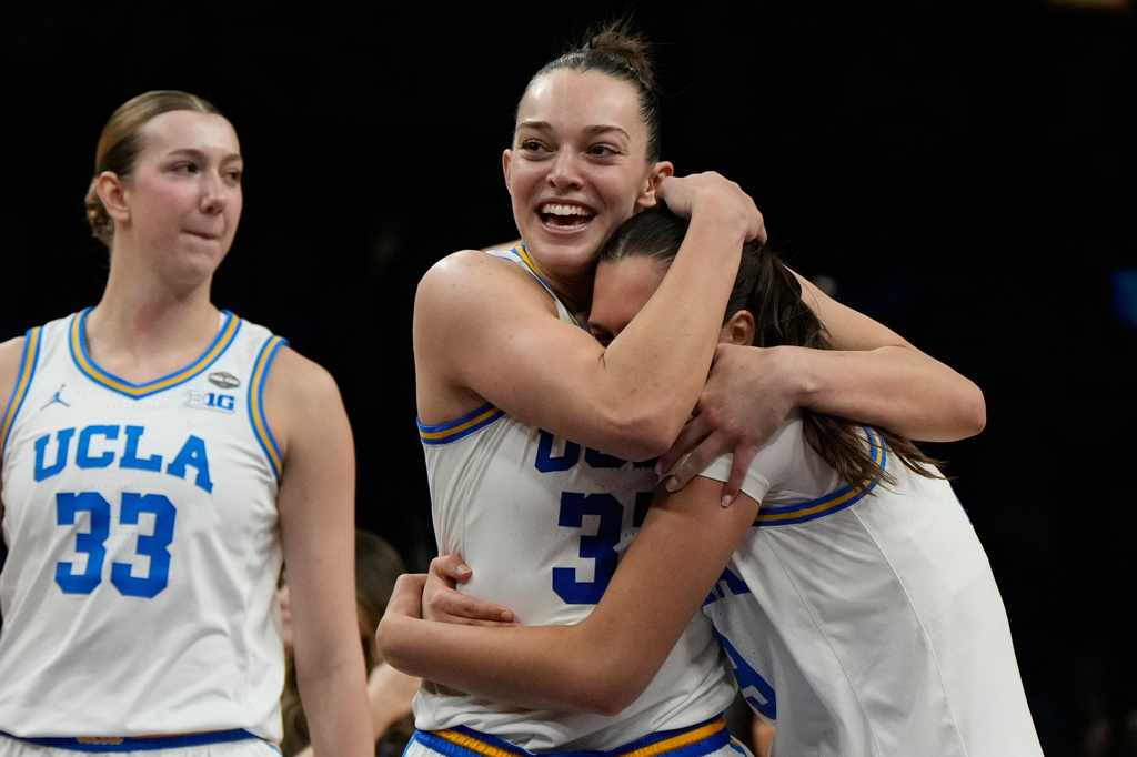 UCLA forward Angela Dugalic, second from left, embraces UCLA guard Lena Bilic (9) after defeating Texas in a women's NCAA college basketball tournament semifinal game at the Final Four, Friday, April 3, 2026, in Phoenix. (AP Photo/Ross D. Franklin)