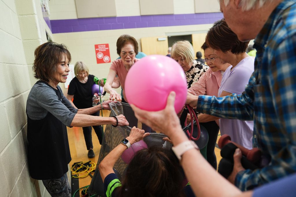 Instructor Bengie Santos, 72, collects small exercise balls in between portions of her exercise class for older adults at the Dale Turner Family YMCA, April 30, 2026, in Shoreline, Wash. (AP Photo/Lindsey Wasson)