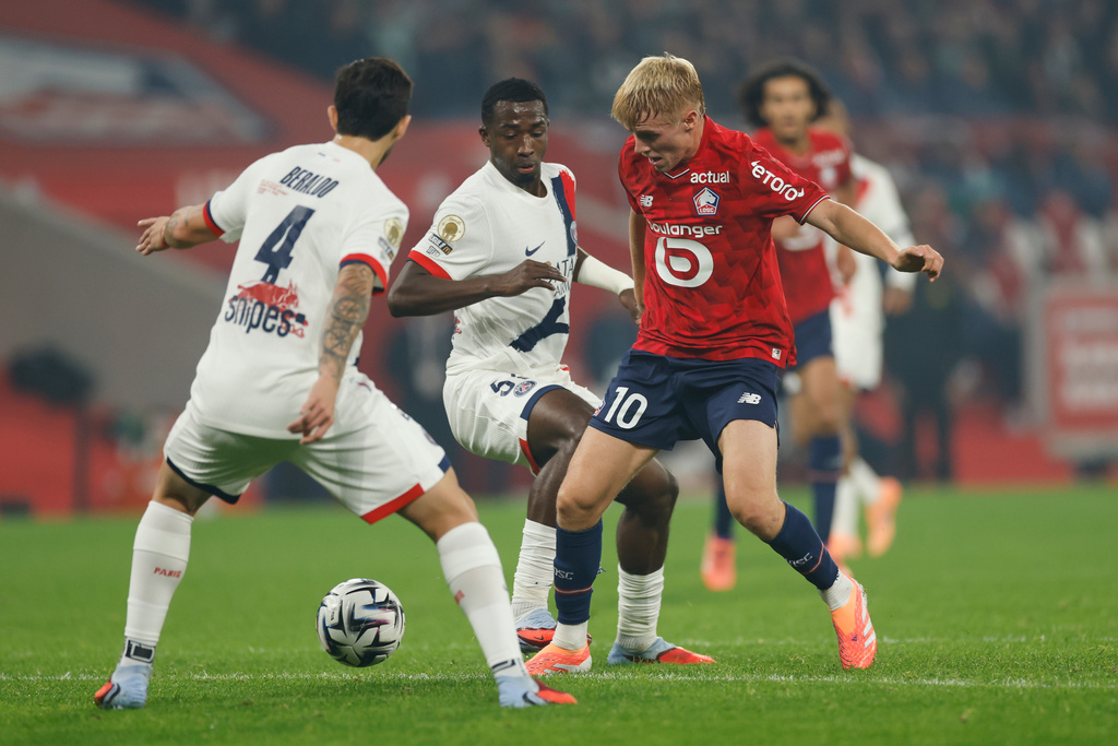 Lille's Hakon Arnar Haraldsson, right, challenges for the ball with PSG's Lucas Beraldo, left, and Willian Pacho during the French League One soccer match between Lille and Paris Saint-Germain at the Stade Pierre-Mauroy in Villeneuve-d'Ascq, outside Lille, France, Sunday, Oct. 5, 2025. (AP Photo/Jean-Francois Badias)