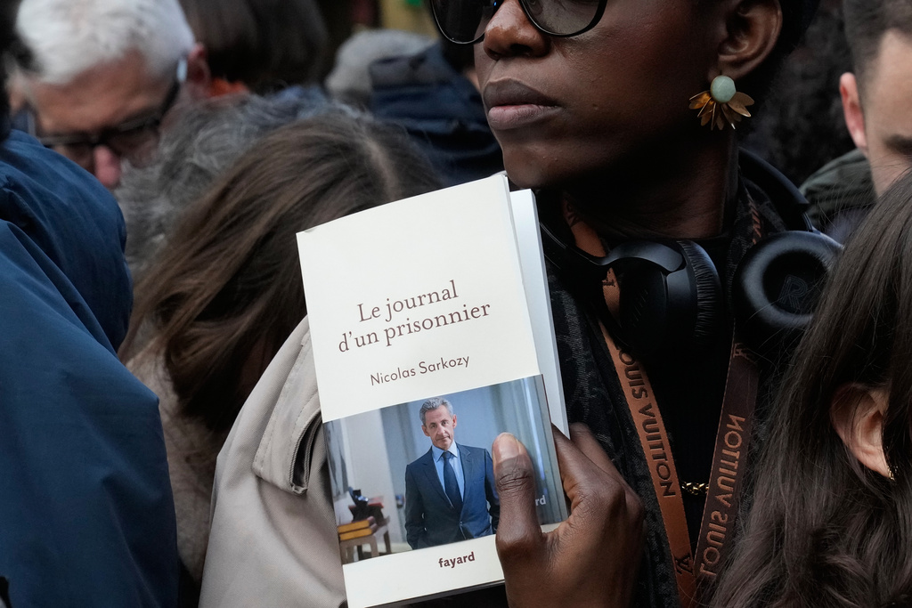 A woman holds a book of former French President Nicolas Sarkozy "Diary of a Prisoner," in front a Paris bookshop, Wednesday, Dec. 10, 2025. (AP Photo/Michel Euler)