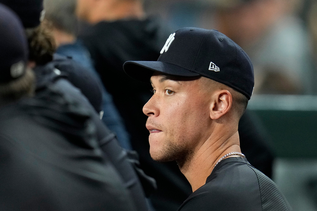 Injured New York Yankees' Aaron Judge sits with teammates in the dugout during the sixth inning of a baseball game against the Arizona Diamondbacks, Friday, Sept. 18, 2026, in Phoenix. (AP Photo/Ross D. Franklin)
